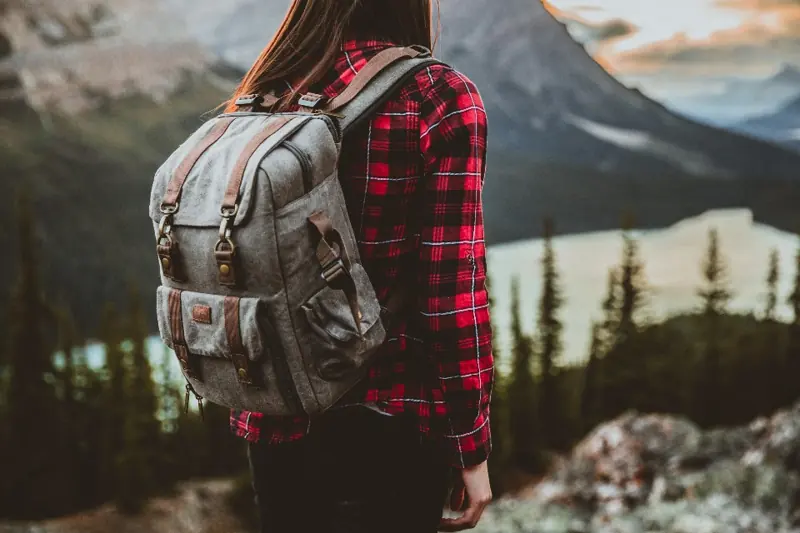 Traveler with a backpack looking at a mountain lake