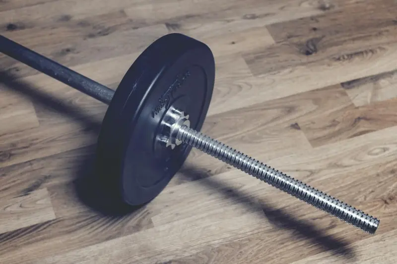 Weight plate and bar on a wooden floor